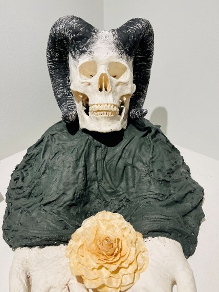 sculpture of a hybrid figure with a skull face and a black robe